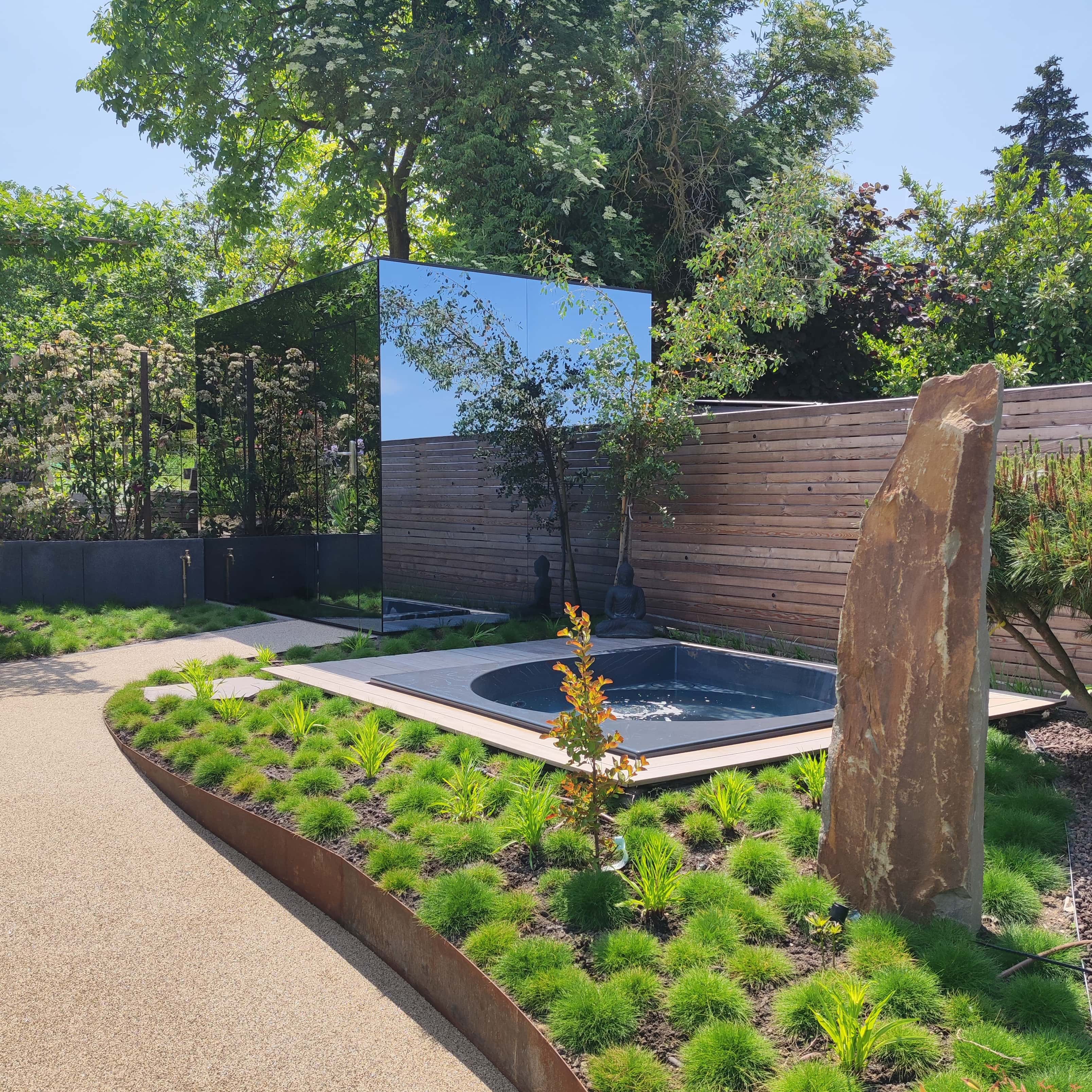 Saunahaus mit Spiegelfassade, daneben ein Whirlpool.